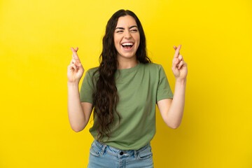 Young caucasian woman isolated on yellow background with fingers crossing and wishing the best