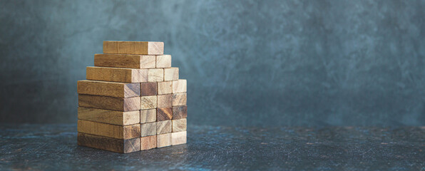 Wooden block stacked pyramid concept of prevent collapse or crash of financial business and risk...
