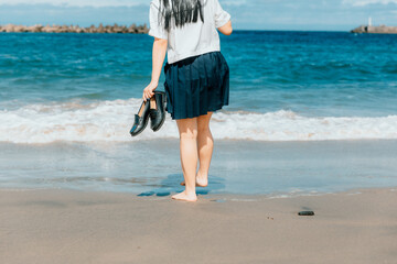 制服で波打ち際に立つ女の子