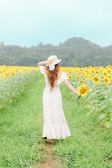 ひまわり畑に立つ女性の後ろ姿