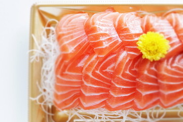 Japanese raw fish,  salmon slices on shaved radish in take out food tray with copy space