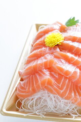 Japanese raw fish,  salmon slices on shaved radish in take out food tray with copy space