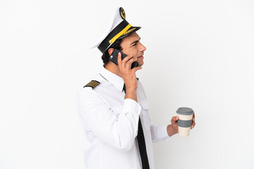 Airplane pilot over isolated white background holding coffee to take away and a mobile