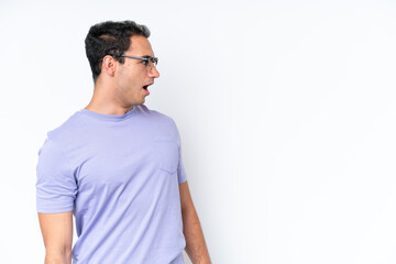 Young caucasian man isolated on white background doing surprise gesture while looking to the side