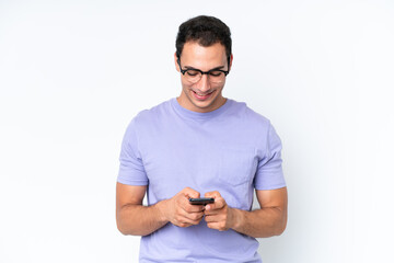 Young caucasian man isolated on white background sending a message with the mobile