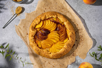 Peach galette with ice cream, homemade round  opened pie with summer fresh fruits, brown sugar, greens, Top view, sunny day, copy space. Homemade dessert on grey table, sweet pastry, French cuisine.
