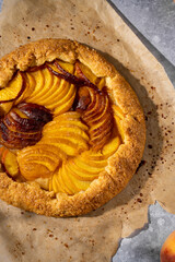 Peach galette with ice cream, homemade round  opened pie with summer fresh fruits, brown sugar, greens, Top view, sunny day, copy space. Homemade dessert on grey table, sweet pastry, French cuisine.