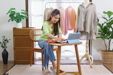 Fashion clothes merchant concept, Female seller measure size of dress and taking notes on notebook