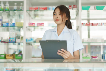 Fototapeta na wymiar Medicine and health concept, Female pharmacist is checking stock medicine on clipboard in pharmacy