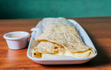 Close up of a Nicaraguan quesillo served on wooden table. Top view of Nicaraguan Quesillo on a plate served on wooden table. Delicious traditional Nicaraguan quesillo served on wooden table