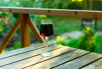 A glass of red wine standing on a wooden table