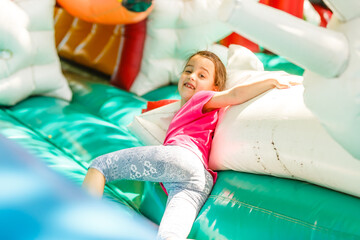 Happy little girl having lots of fun on a jumping castle during sliding.