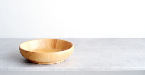 Empty round wooden plate on white cement table and white wall background, Blank wood tray banner for food display montage, template, mock up