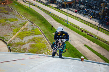Male worker inspection wearing safety first harness rope safety line working at a high place on tank roof spherical