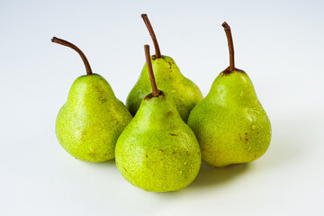 Green Williams pears isolated on a light surface in close-up. Several ripe fruits of yellow-green color covered with water droplets are on the table