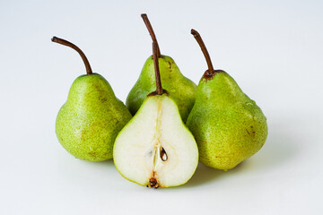 Whole pears and in section, Williams variety, yellow-green ripe juicy fruit covered with water droplets, lying on a light monotone surface, close-up