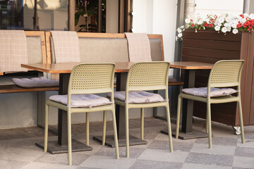 Empty table and chairs on the summer terrace near a small cafe. The restaurant is open and waiting for guests. A laid cafeteria table outside.
