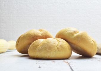 Small round loaves on light colored rustic table.