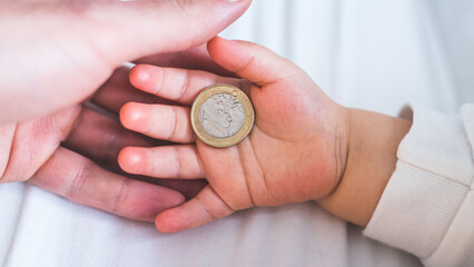 Inflation and financial security concept: Close up of newborn baby holding a euro coin