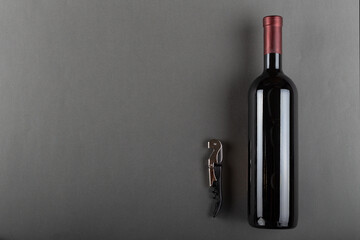 Corked bottle of red wine and corkscrew on a gray background. Alcoholic drink. Winemaking concept. Space for text.