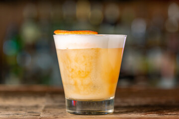 Vanilla Sour cocktail with egg white and lemon juice  on the bar.