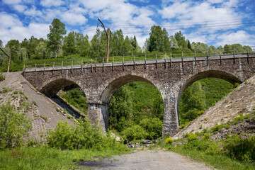 Fototapeta na wymiar Old road bridge in knightly style. Beautiful summer landscape in Europe. Horizontal photos of architectural structures.
