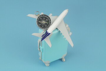 Airplane and compass on travel suitcase on blue background. Vacation, journey and travel trip concept. 