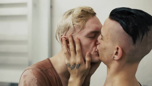 Gay couple hugging each other kissing on the lips close up