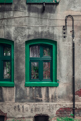 Fototapeta na wymiar A green window with a green window sill against the background of a gray, plastered, damaged wall