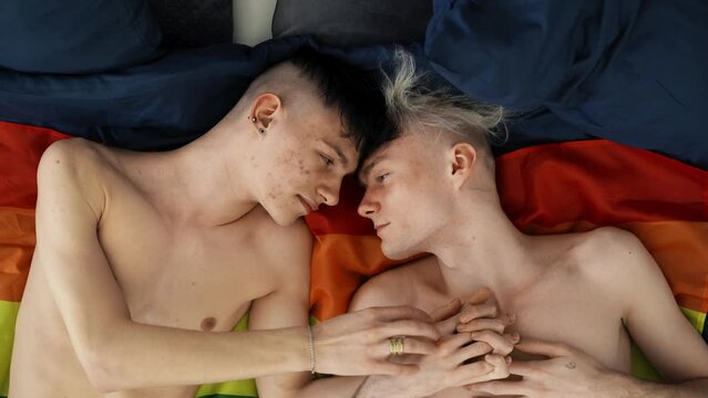 Two gay men lovers laying side by side on flag, LGBT concept, slow motion