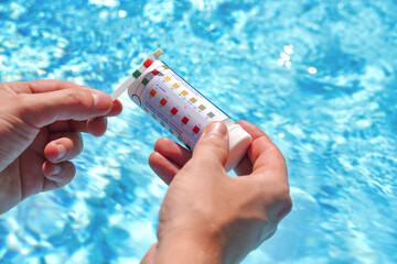 Checking the water quality of a pool with the help of a test strip with PH value, chlorine and algaecide - obrazy, fototapety, plakaty