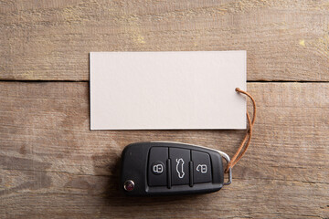 Car insurance or rent concept. Vehicle security key with blank tag on the wooden background - 523325814
