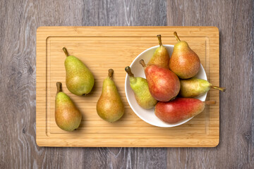 Ripe juicy pears in a bowl on a wooden background, top view