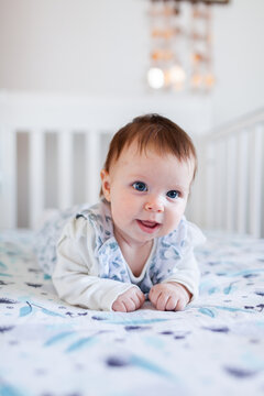 Happy Aussie baby smiling at tummy time in cot in bedroom