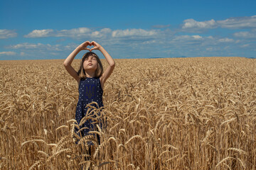 Ukrainian girl is in the field of wheat. The child prays for peace in Ukraine.