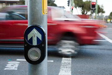 Traffic pedestrian crossing light button with cars zooming past