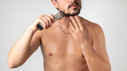 Shaving and styling a beard and mustache, a bearded guy with a razor in his hand