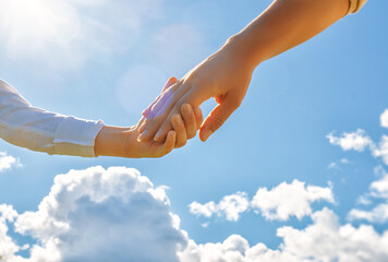 Hands of adult and child on blue sky background