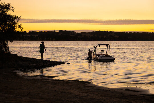 couple with speedboat at boat ramp on lake at sunset