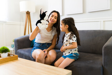 Latin mom using a puppet to tell a story to her little daughter