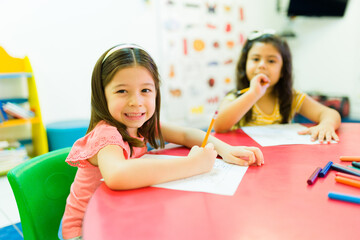 Happy little girls coloring in kindergarten