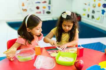 Diverse preschool girls sharing their lunch food