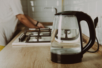 Modern electric transparent kettle on a wooden table in the kitchen.Kettle for boiling water and making tea.Home appliances for making hot drinks.Space for copy.Place for text.