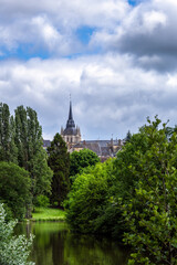 Fototapeta premium View of Fresnay-sur-Sarthe church tower among the trees in spring, Sarthe, France
