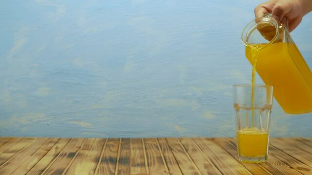 Fresh orange juice being poured in a glass. Homemade fruit juice on table. Organic vitamin drink. Place for your text.