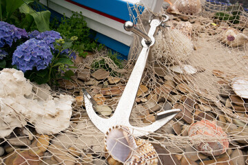 Fototapeta na wymiar Anchor, fishing net, sea pebbles and shells close-up.