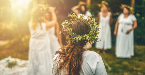 Women in flower wreath on sunny meadow, Floral crown, symbol of summer solstice.