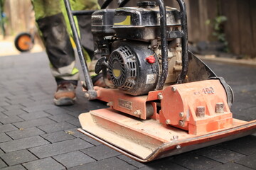 Laying paving stones. compaction of paving stones with a compactor - obrazy, fototapety, plakaty