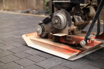 Laying paving stones. compaction of paving stones with a compactor - obrazy, fototapety, plakaty