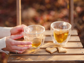 Drinking tea with cookies on wooden table. Cozy autumn mood scene in autumn park